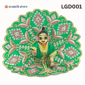 A small, brass Laddu Gopal (baby Krishna) deity idol is seated and dressed in a vibrant green poshak (outfit). The outfit is heavily adorned with intricate gold embroidery, silver sequins arranged in diamond patterns, and pink leaf-like designs. The deity has large, expressive eyes and a tilak on the forehead. The background is plain white, with a "Swastik Store" logo in the top left corner and the product code "LGD001" in the top right. - Swastik Store